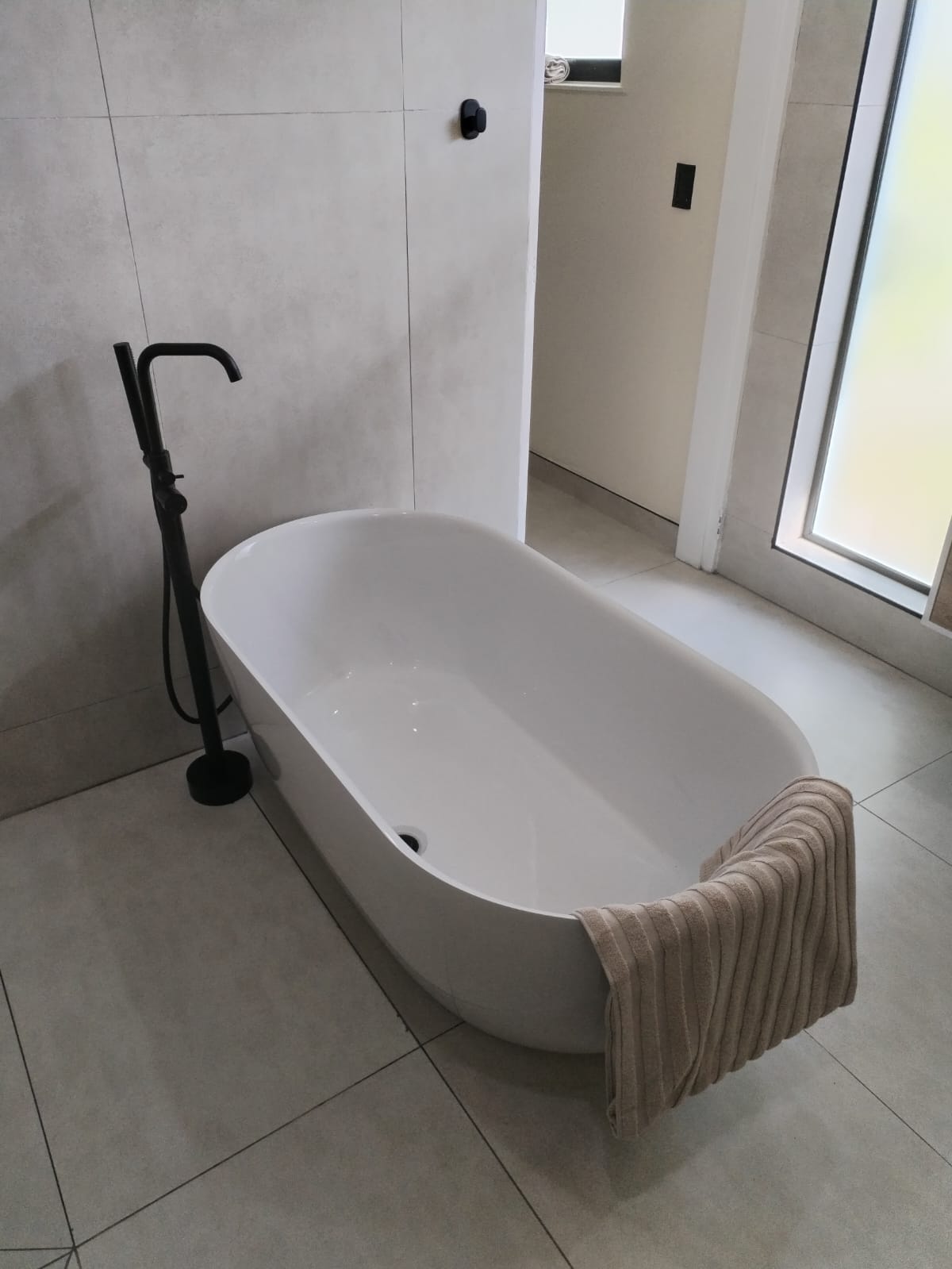 Freestanding bath with matte black floor-mounted mixer